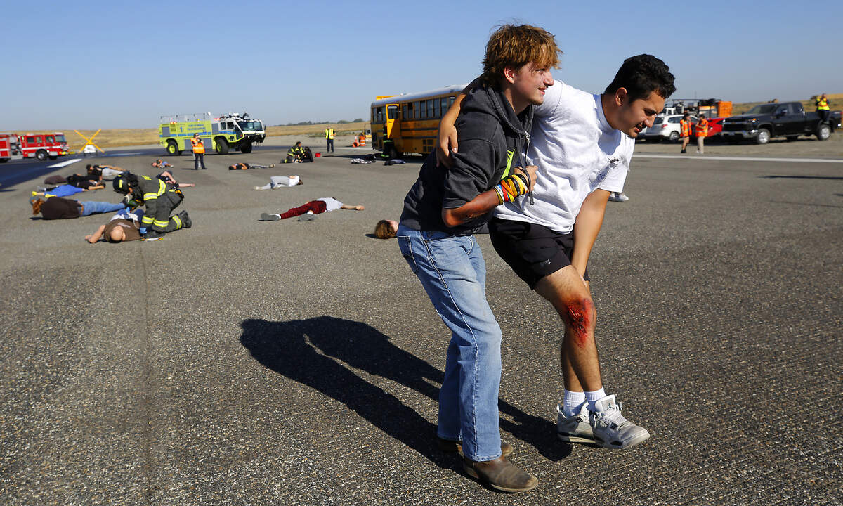 Mock airplane crash victims, portrayed by Tri-Tech Skills Center firefighting and emergency medical services high school students, hobble away from the crash scene after being triaged by Pasco firefighters at Wednesday morning's training exercise at the Tri-Cities Airport in Pasco. The FAA requires that the airport practice a full-scale emergency response exercise every three years.