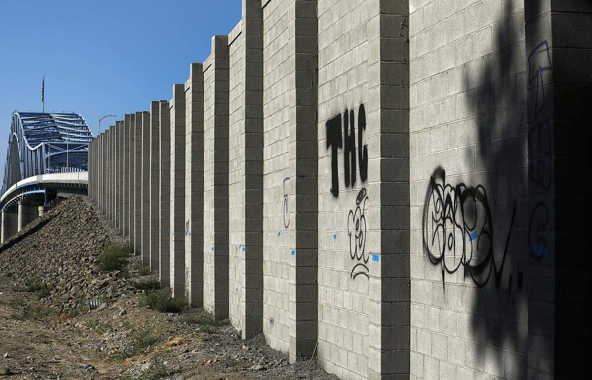 Graffiti has been painted on both sides of the new concrete block barrier sound wall at the base of the blue bridge in Pasco.