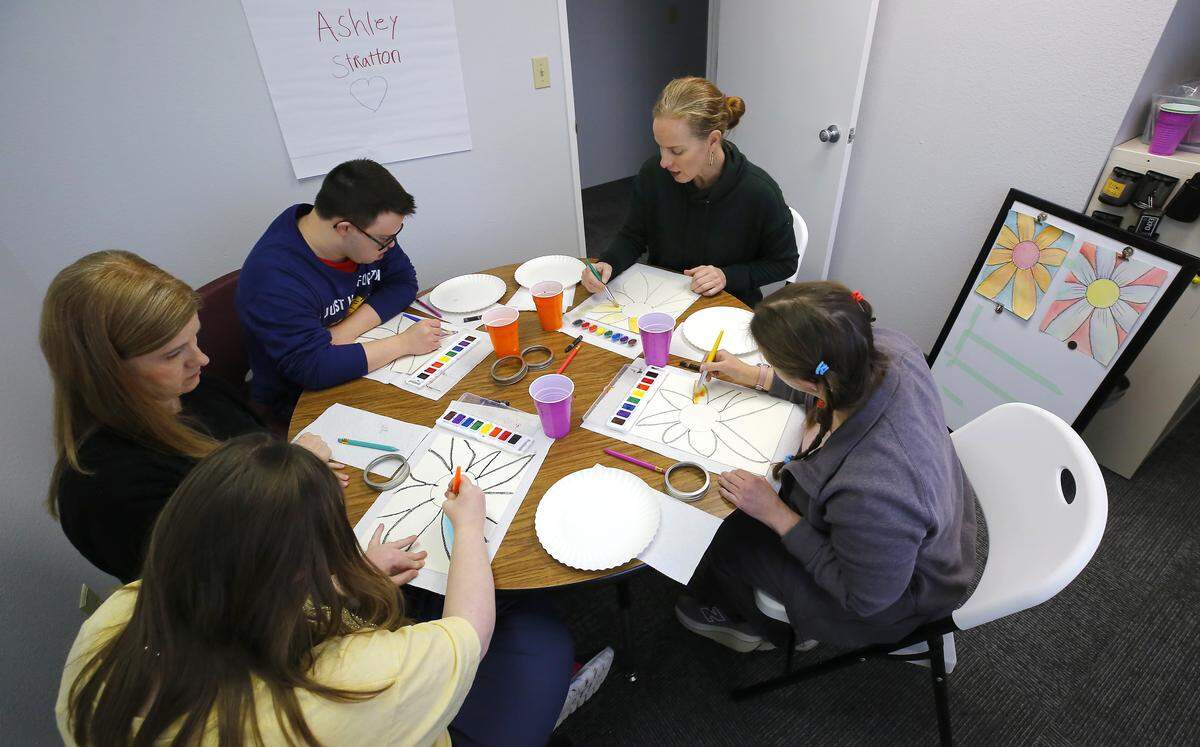 Teacher Ashley Stratton joins students working on a watercolor art project recently at the new Beautiful Day Learning center. Julie Sumsion, founder and head teacher, kneels, at left, between student Brady Cleveringa and her daughter, Aidan. Student Melissa Sprague, wearing pig tails,  brushes color on her paper, at right.  The new facility, designed to provide ongoing education for adults with intellectual disabilities, is  at 5917 W. Clearwater Ave. building B in Kennewick.