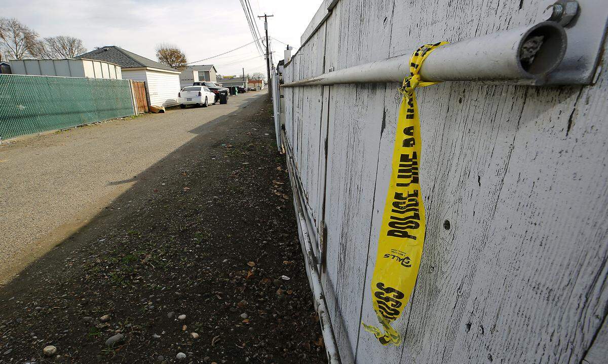 Crime scene tape hangs from a fence in an alley south of Sylvester Street where a stabbing took place.