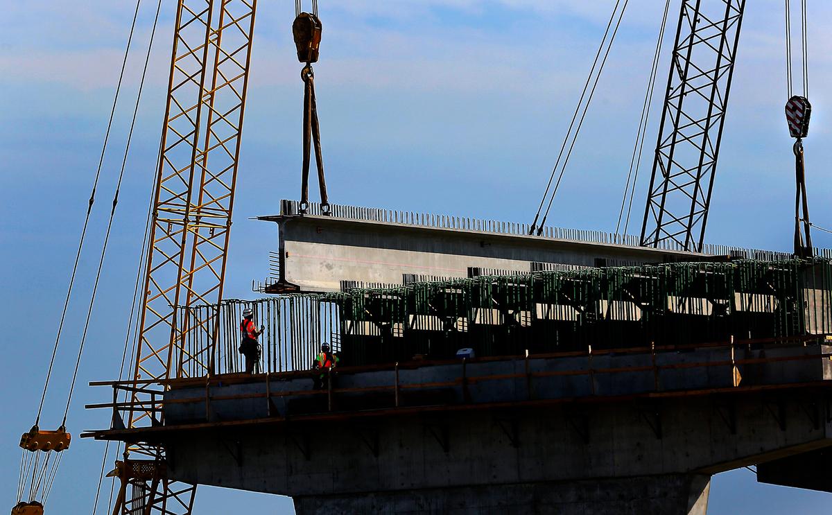 Large cranes and construction workers place the first set of girders on a concrete support column at the site of the Lewis Street overpass being built to replace the 1937 underpass in downtown Pasco. 