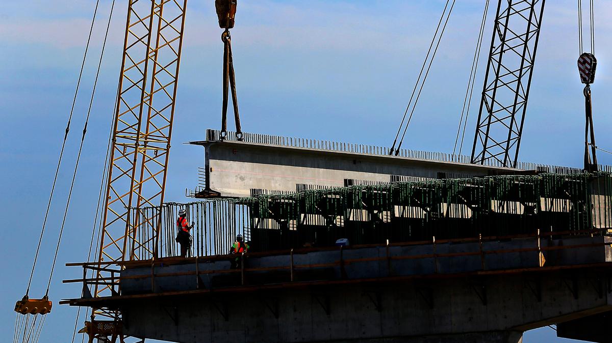 Large cranes and construction workers place the first set of girders on a concrete support column at the site of the $36 million Lewis Street overpass being built to replace the 1937 bridge in Pasco. The new road will go over the BNSF tracks near Oregon Avenue. The project is expected to be done by next fall.