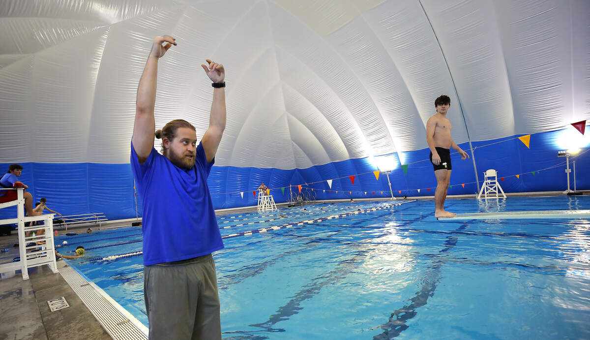Richland dive coach Mitch Piper, demonstrates proper form for one his team's athletes as they practice recently inside the nearly $2 million bubble dome over the Olympic-sized pool at Pasco's Memorial Pool.  The dome towers at 38-feet high, 113-feet wide and 200-feet long is supported by air pressure.