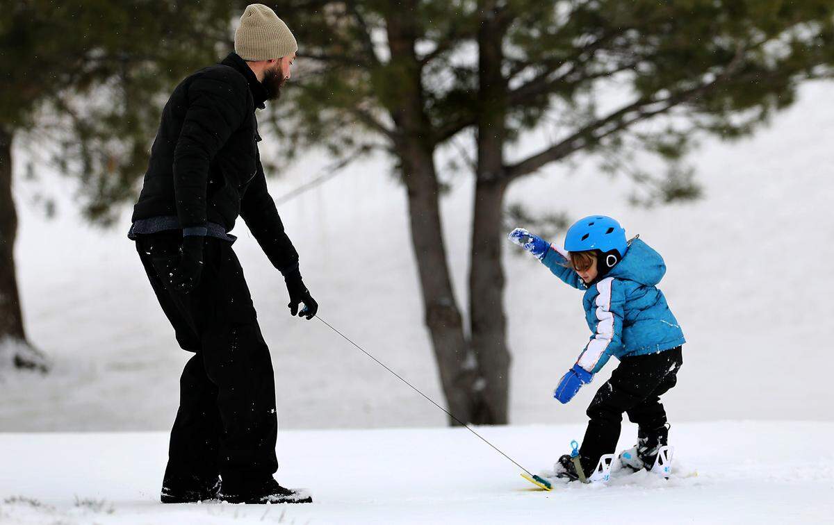 Four-year-old Cyrus Door windmills his arms fighting to maintain his balance Friday morning as his father, Jason, pulls him on a snowboard up a snow covered hill in Canyon Lakes of south Kennewick. An overnight coating of snow across the Tri-Cities provided the slippery outdoor playground.