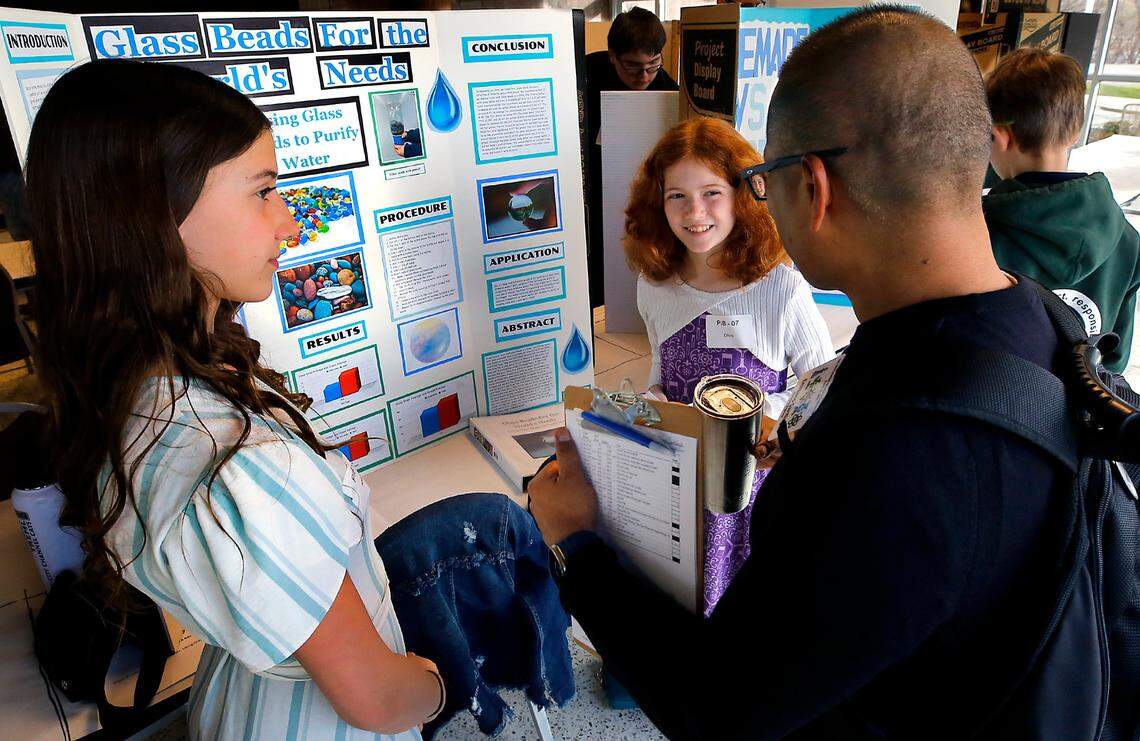 Abigail Treml, left, and Olivia Kreitzberg, sixth-grade classmates at Christ the King private school, answer questions about their science project called “Glass Beads for the World’s Needs” from judge Emiliano Santiago, an electriclal engineer at PNNL, during the 70th annual Mid-Columbia Regional Science and Engineering Fair.