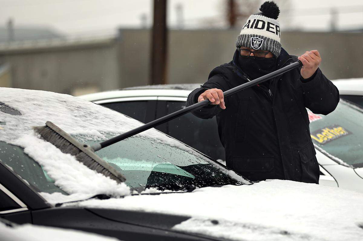 Amadeo Salazar bundles up early Friday morning while clearing snow off the vehicles at the VIP Motorsports sales lot on West Columbia Drive in downtown Kennewick. More snow is possible Saturday, according to the weather service.
