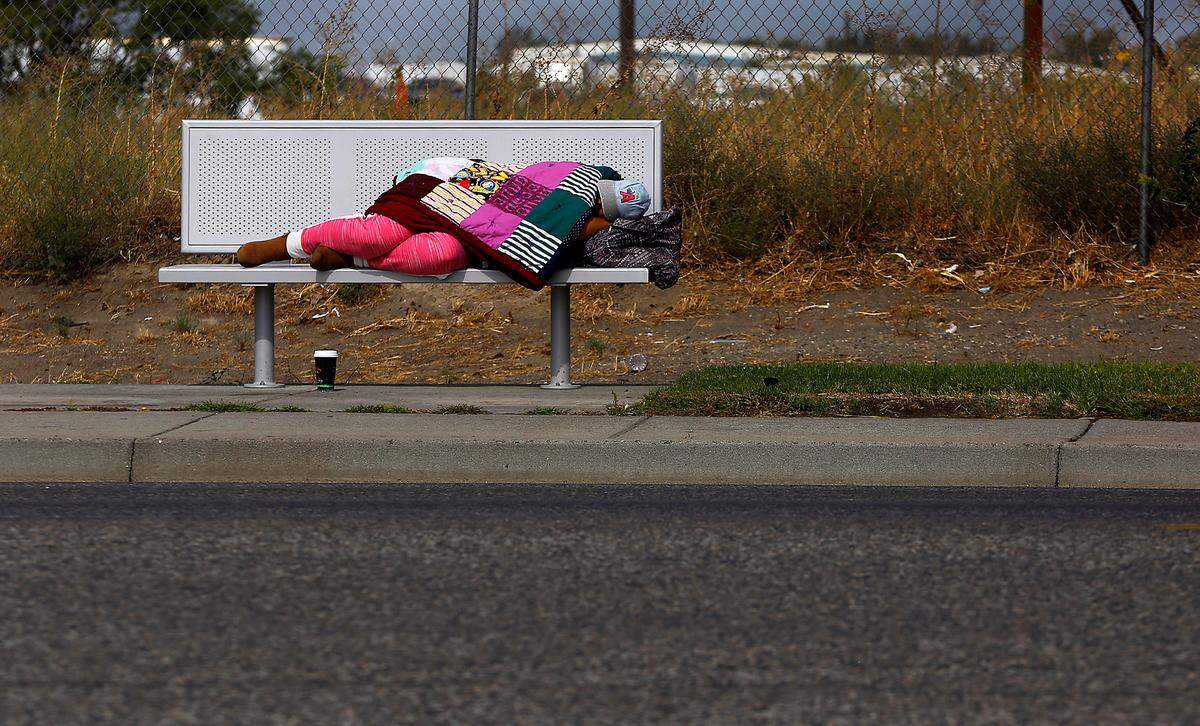 A woman sleeps on a transit stop bench on East Lewis Street in Pasco in September 2022.