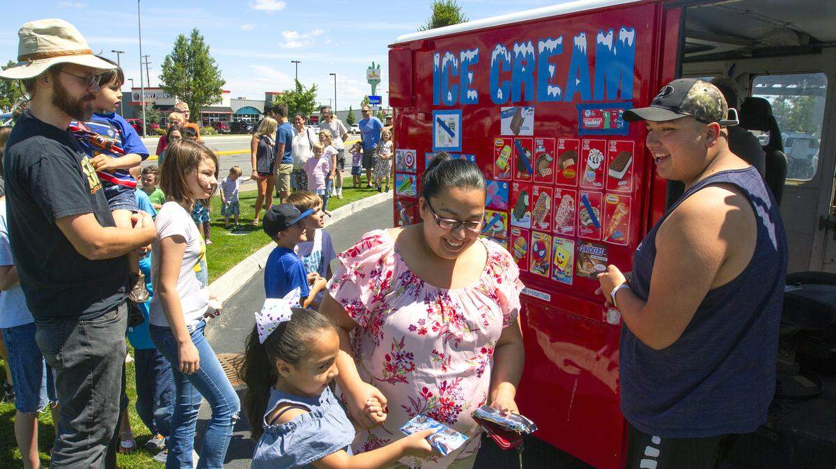 People line up with their kids outside of HAPO Community Credit Union's business center in Kennewick for free ice cream from the Little Red Ice Cream Truck on Friday.