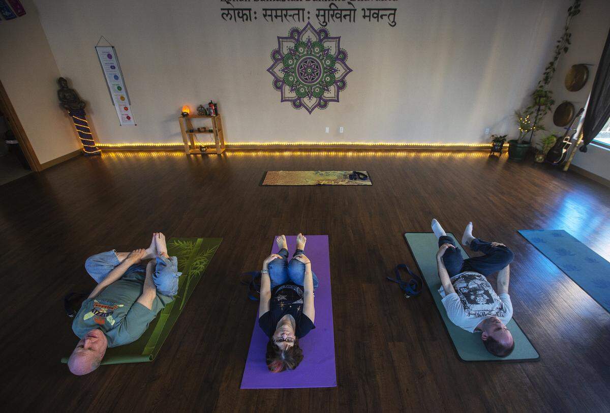 The Arc of Tri-Cities’ clients Greg Berg, left, Linda Mann, center, and Shawn Sorenson, stretch inside The Lotus Pad in Kennewick.