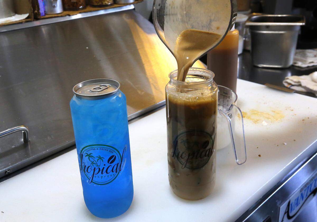 Employees at Tropical Express Coffee and Drink Bar fill clear plastic cans with colorful drinks at their location on West Skagit Avenue in Kennewick. A special machine is used to attach the aluminum lids.
