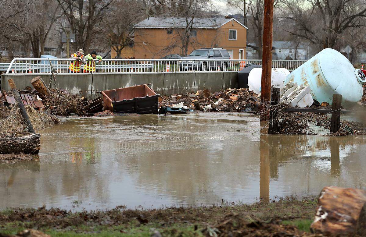 WSDOT workers Cody Ford, left, and Daniel Andrew look at the the box culvert bridge choked with debris from Yakima River floodwaters Monday on Van Giesen Street near Buckskin Lane in Richland.  