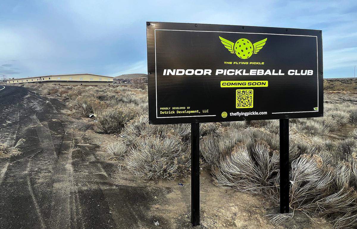 A sign posted in a vacant lot off Wiser Parkway in west Kennewick advertises for a new indoor pickleball club called The Flying Pickle. The new building, adjacent to QUAKE Family Fun Center, is being constructed by Detirck Development, LLC.