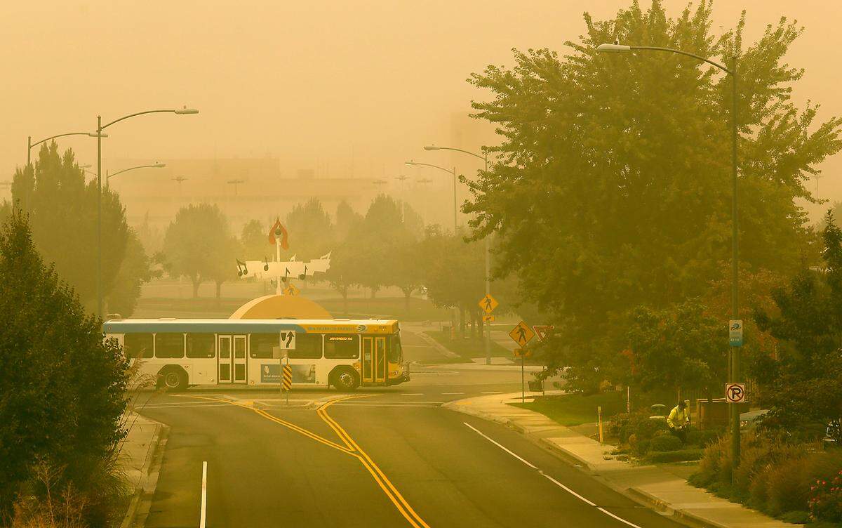 A Ben Franklin Transit bus navigates the roundabout on North Young Street at Grandridge Boulevard Monday morning as a thick layer of wildfire smoke blankets the Tri-Cities. The outline of the Benton County Justice Center is barely distinguishable in the background through the hazy conditions.