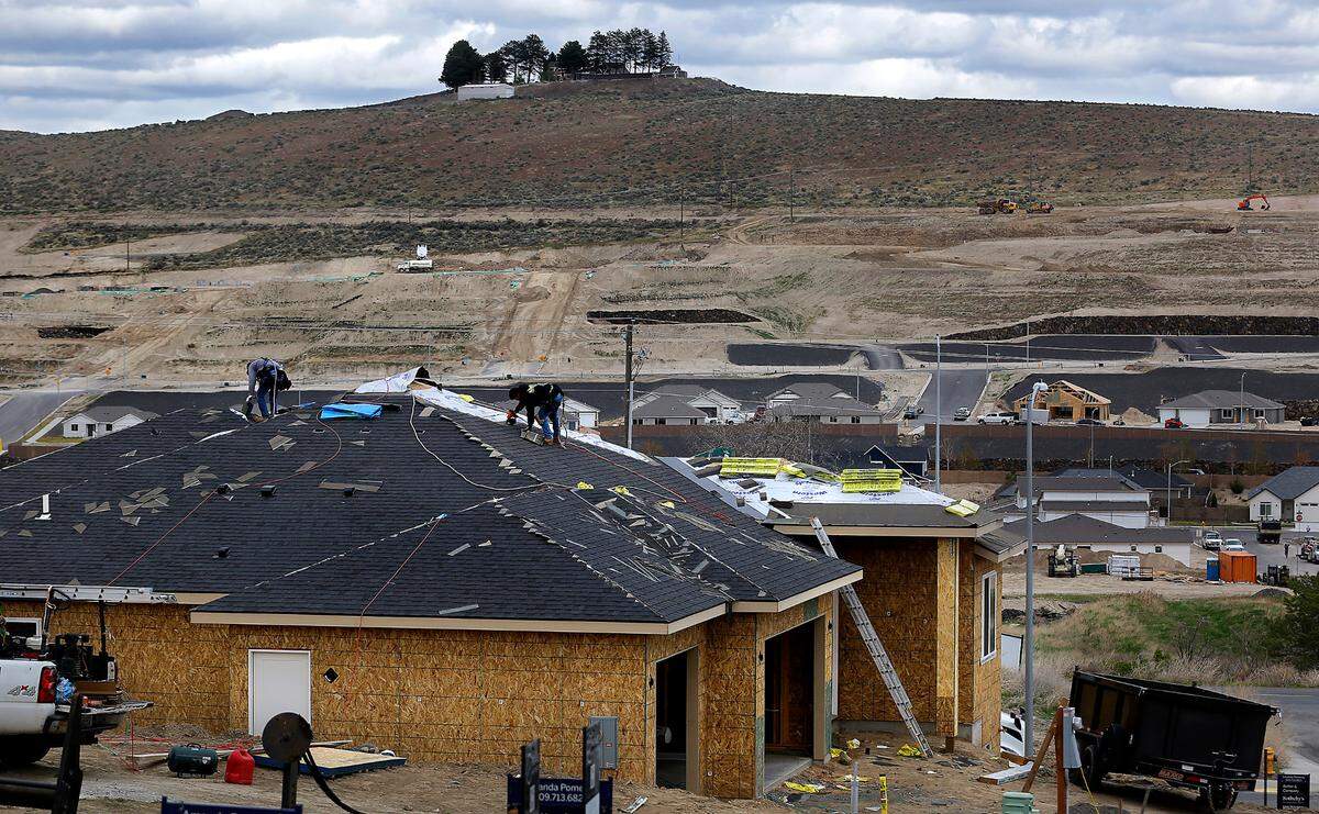 Construction workers install a roof on a home under construction in the 3700 block of South Nelson Street in Kennewick.