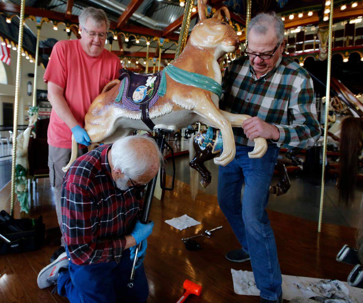 Volunteers Richard Smith, left, and Pat Nagle work together with artist Mike Thornton Wednesday to install his latest carving onto the Gesa Carousel of Dreams in Kennewick. 