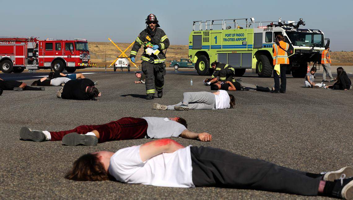 Pasco firefighters begin triaging mock airplane crash victims, portrayed by Tri-Tech Skills Center firefighting and emergency medical services high school students, during Wednesday morning's training exercise at the Tri-Cities Airport in Pasco.