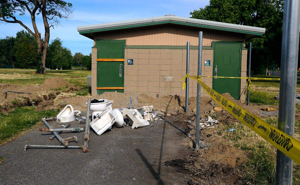 Old bathroom fixtures sit on the ground outside a bathroom building near the recently installed fence post for the city of Kennewick’s new dog park being constructed in the east end of Columbia Park.