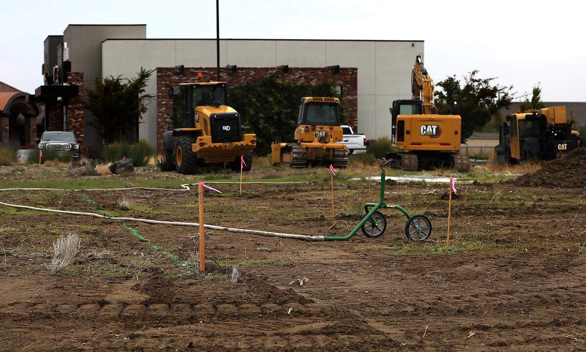 Heavy earthmoving equipment sits in a vacant field near survey sticks for new construction near West 26th Avenue and South Union Place in Kennewick. The work is for a new 7,800-square-foot multi-tenant retail building in Kennewick’s Southridge area.