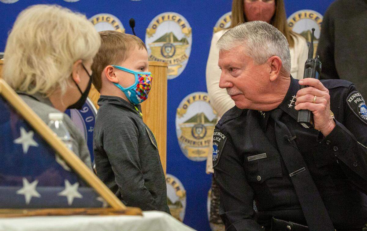 Kennewick Police Chief Ken Hohenberg looks at his oldest grandson, Max, 5, as they listen to the response to Hohenberg’s final radio call to 911 dispatchers following the dedication of the Kennewick Police Station building which was renamed in his honor. Kennewick Police Chief Ken Hohenberg gave his final radio call to Tri-Cities dispatch following a ceremony celebrating the official dedication and renaming of the Kennewick Police Station building in his honor Thursday. He served the city of Kennewick for 44 years, including 18 years as chief. His last day is Feb. 28.
