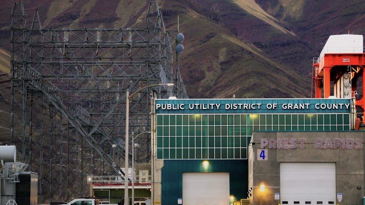 Large transmission lines at the Priest Rapids Dam, with the Saddle Mounts visible on the south bank in the background. The hydroelectric facility is owned and operated by Grant County Public Utility District and sits northwest of the Tri-Cities.