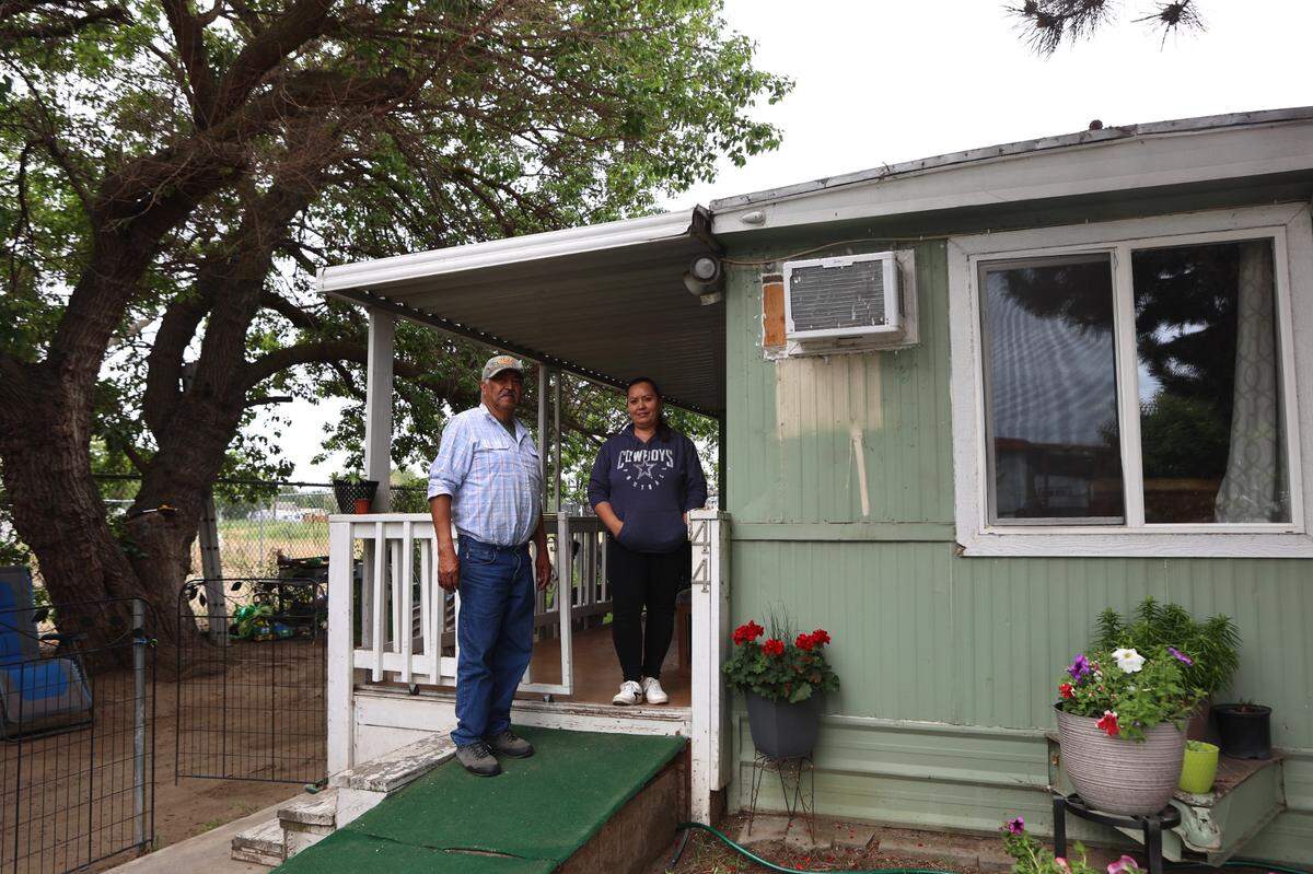 Jose Diaz Gonzalez and his daughter-in-law Irene Soltero stand on the front porch of their family’s home at Sands Mobile Home Park in Pasco.