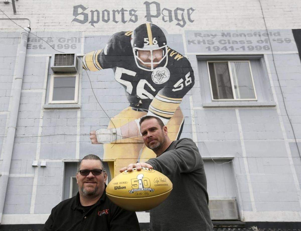 Former Kennewick High Athletic Director Ronnie Coleman, left, and Head Football Coach Bill Templeton pose for a photo in 2016 with the golden Wilson NFL football at the Ray Mansfield mural in downtown Kennewick.