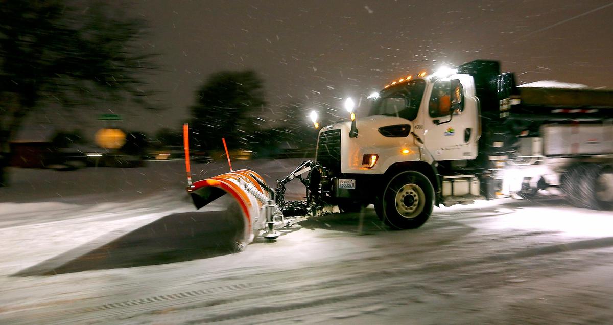 A city of Kennewick snowplow illuminates the pre-dawn darkness as it works its way south on Dayton Street.