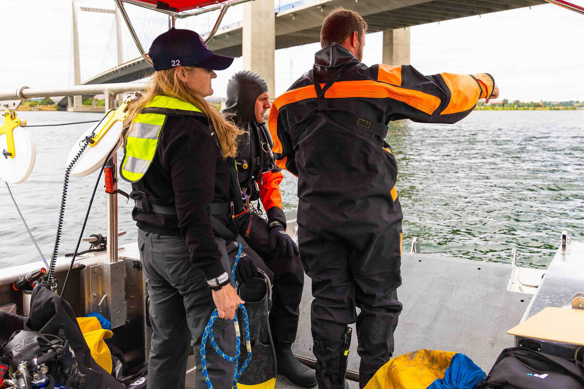 Columbia Basin Dive Rescue members Jessie Bell, left, Ben Prueitt, center, and Cyrus Stanley discuss the next underwater search area Sunday before entering the Columbia River near the cable bridge.