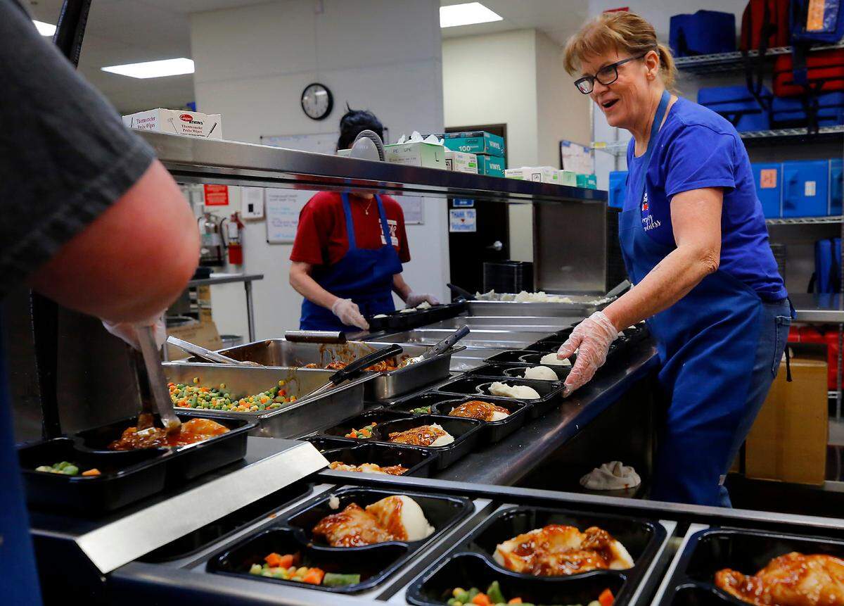 Volunteer Josie Beach wears a smile while helping fill over 300 trays of meals to be frozen and delivered later to area senior citizens through the Mid-Columbia Meals on Wheels program.