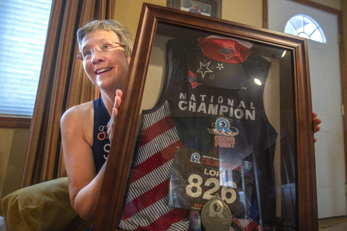 Lori Selby holds up a shadow box of her jersey and medal for when she competed in Rev3 Cedar Point Triathlon.