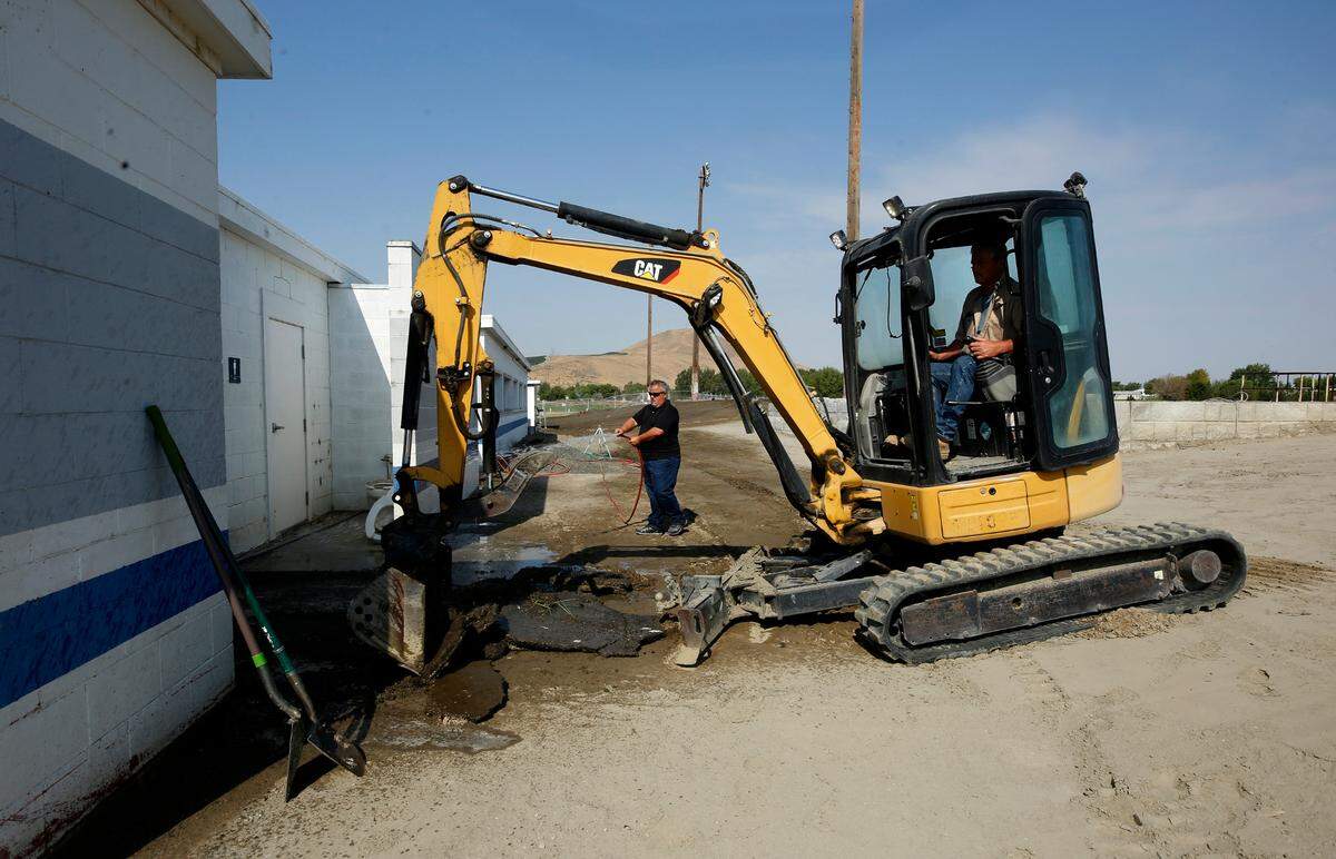 Volunteers Jesse Brown, left, and Tim Babcock, owner of Vision Enterprises in Kennewick, work to remove asphalt from the concession and ticket sales building at the Tri-City Raceway site in West Richland. The work is part of the renovation of the track since the facility was closed about 17 years ago.