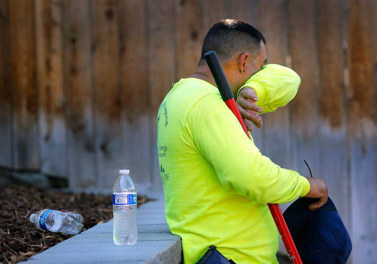 Landscaping worker Gilbert Alvarado, an employee of Gamache Landscaping Inc., wipes sweat from his brow after shoveling decorative river rock at a backyard landscaping project in south Richland. Many outdoor workers are starting early to end their shifts early to help avoid the hottest parts of the day.