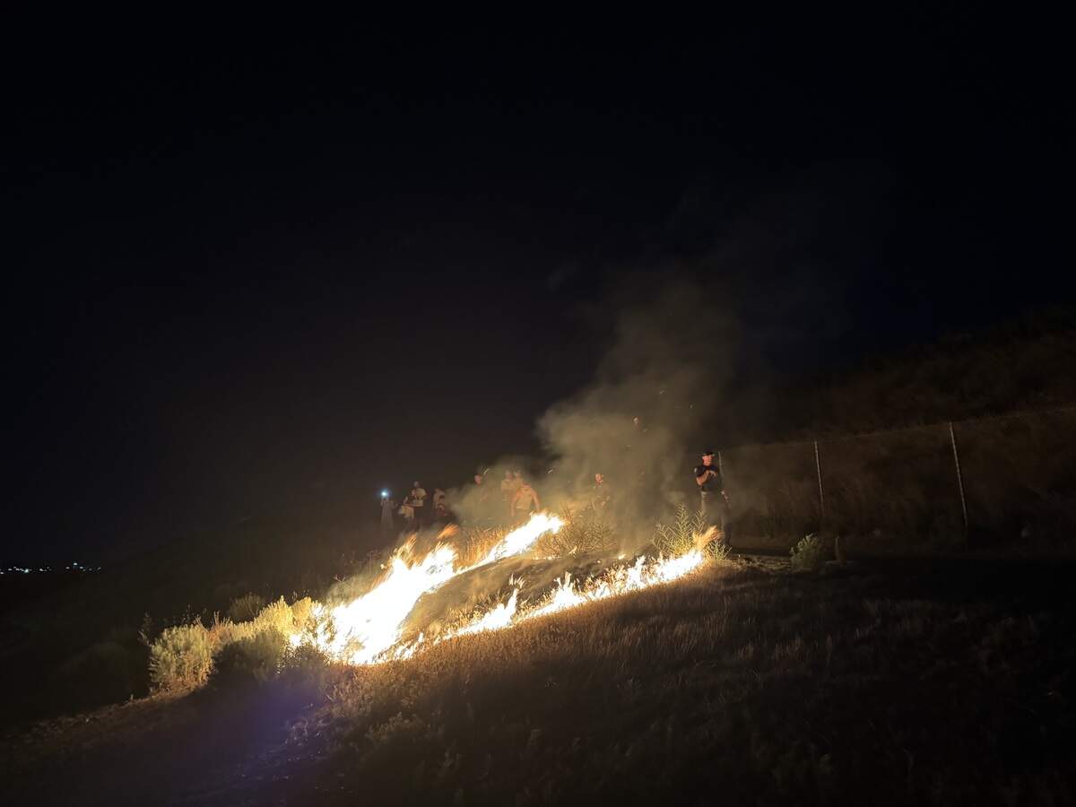 A brushfire flared up after gusts of wind carried embers from fireworks onto the embankment of the Interstate 182 bridge at Columbia Point Marina Park in Richland on July 4.