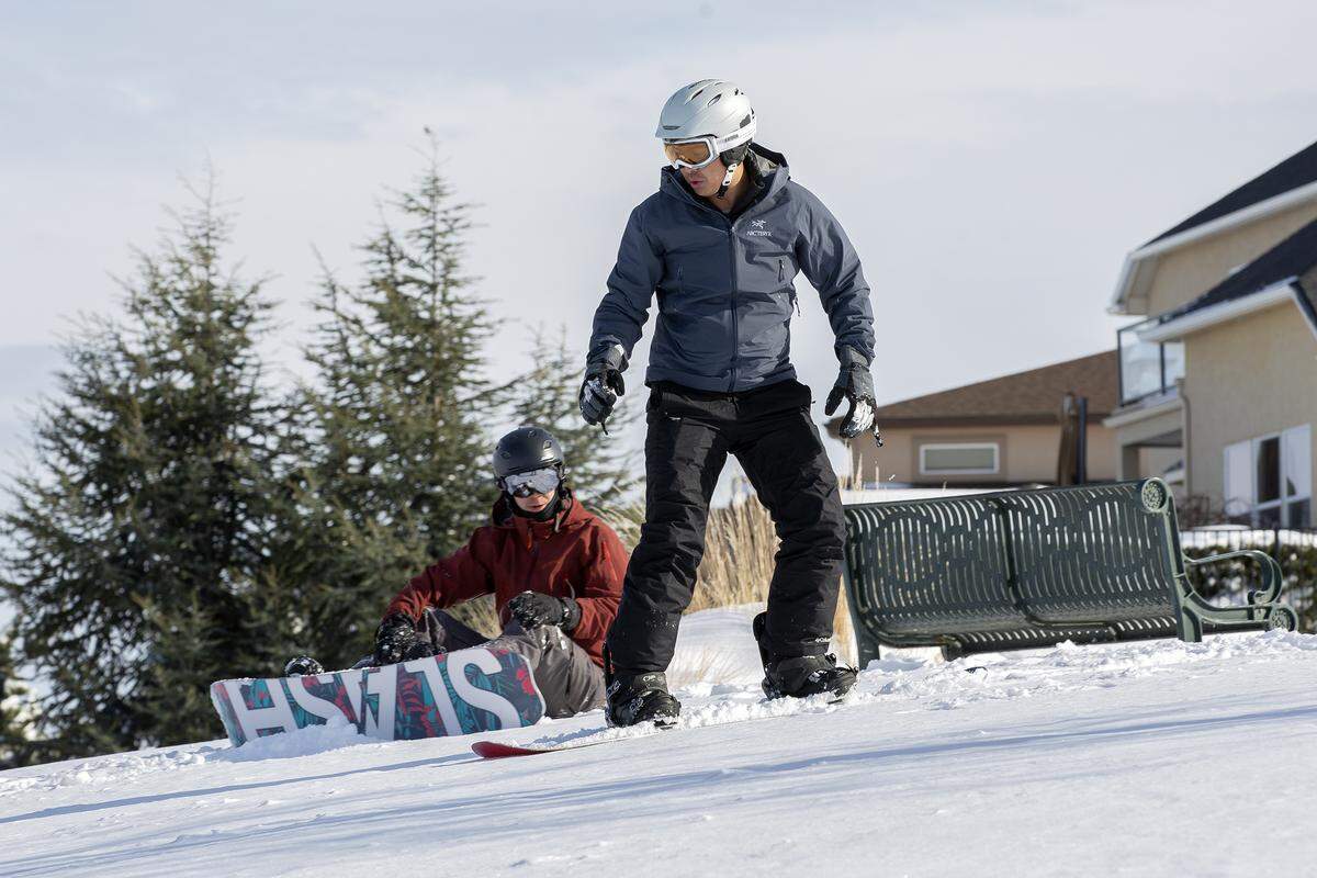 John Schilling sits and watches as Jimmy Zhao snowboards near Badger Mountain in Richland on Tuesday. Schilling was teaching Zhao the basics of snowboarding.