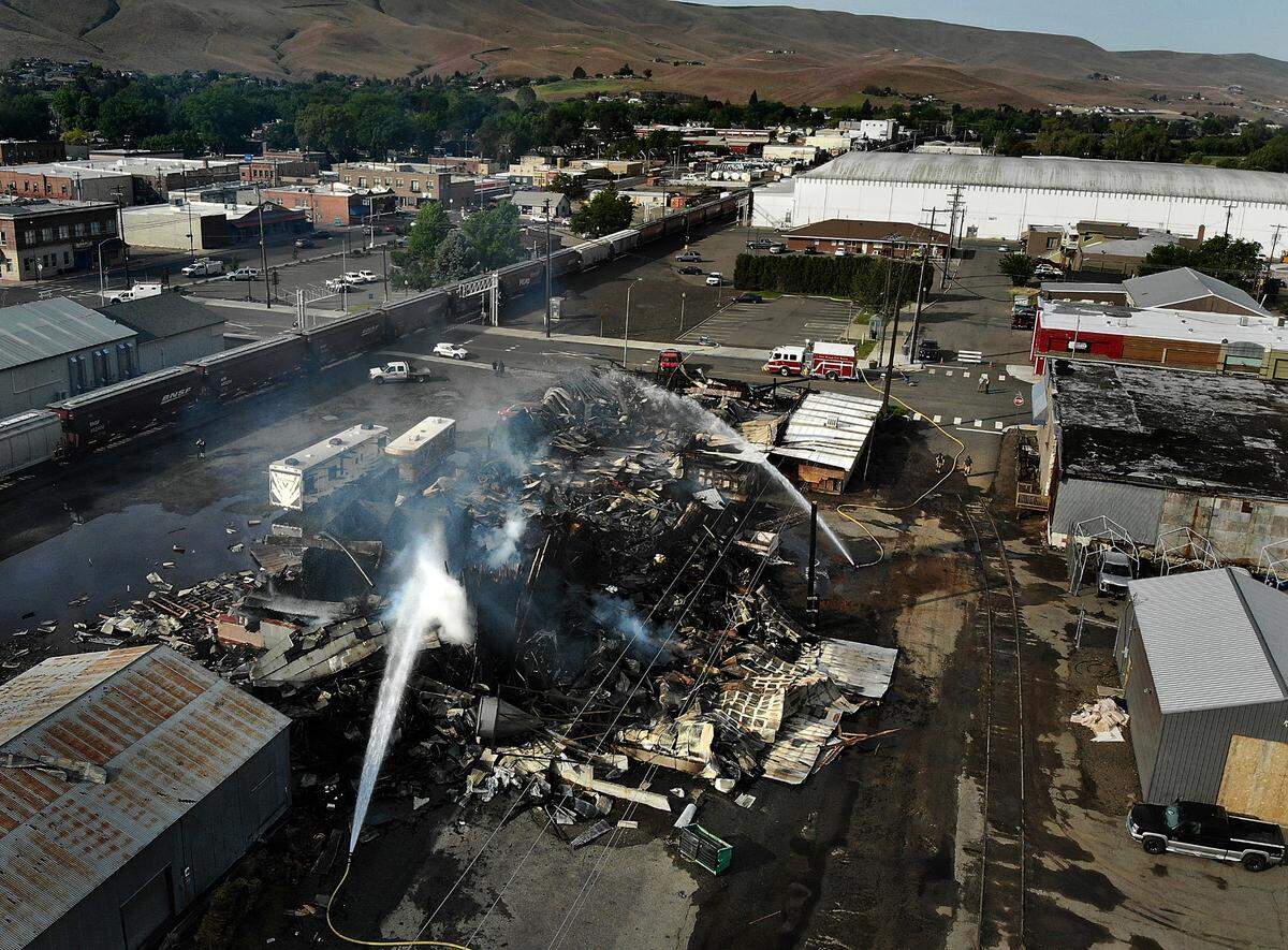 A smoldering pile of twisted metal and charred lumber is all that remains Thursday morning of the M & E Seed and Grain Co. in downtown Prosser after firefighters battled the fire all night. The blaze reportedly left one person with burns.