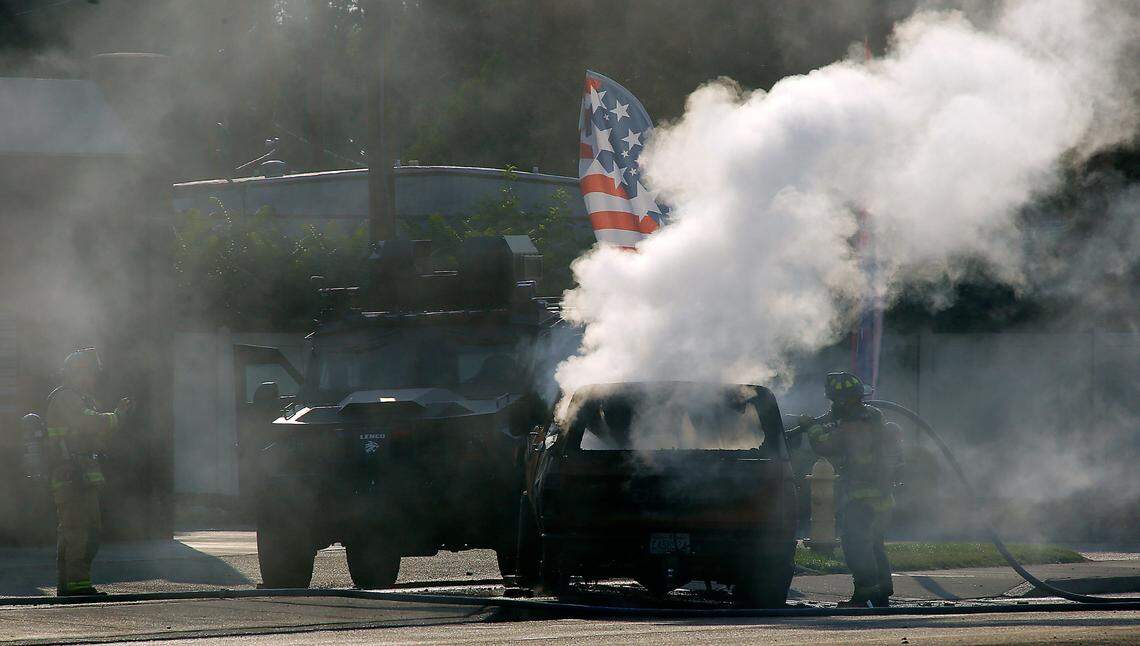 Firefighters extinguish a burning pickup truck near The Wash Stop car wash in West Richland. The fire is connected to a violent rampage that stretched from Finley to West Richland ended with an officer-involved shooting.