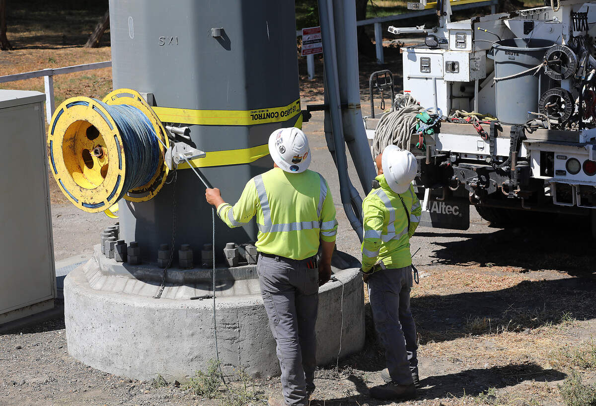 DJ's Electrical employees attach a spool of rope to a large diameter pole on the Kennewick shoreline Tuesday that will be used in the process of replacing the high tension power line damaged by last week's floatplane crash.