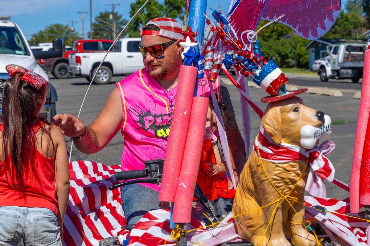 A family rides a patriotic-themed parade entry Saturday during the Benton City Fourth of July Parade. Decorated with red, white and blue bunting, the entry reflected the hometown spirit of the annual Independence Day celebration.