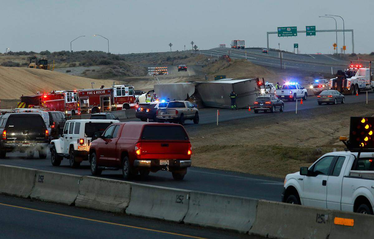 An overturned semi-truck blocks the northbound lane of Highway 395 at Ridgeline Drive as southbound drivers slowly make their way past the early Thursday morning crash in Kennewick.