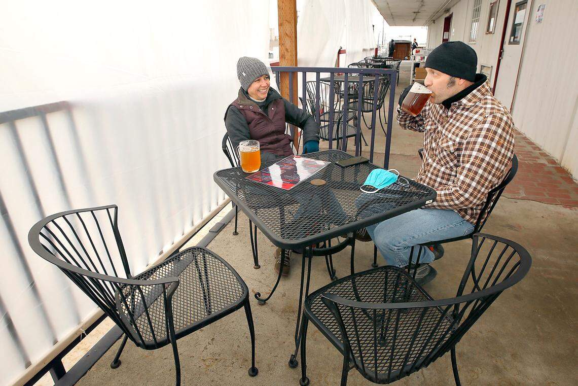 Bundled up and dressed in layers, Alisa and Jeffery McComb of Kennewick sit in the plastic wrapped outdoor seating section during lunchtime at Ice Harbor Brewery at 206 N. Benton St. in Kennewick.