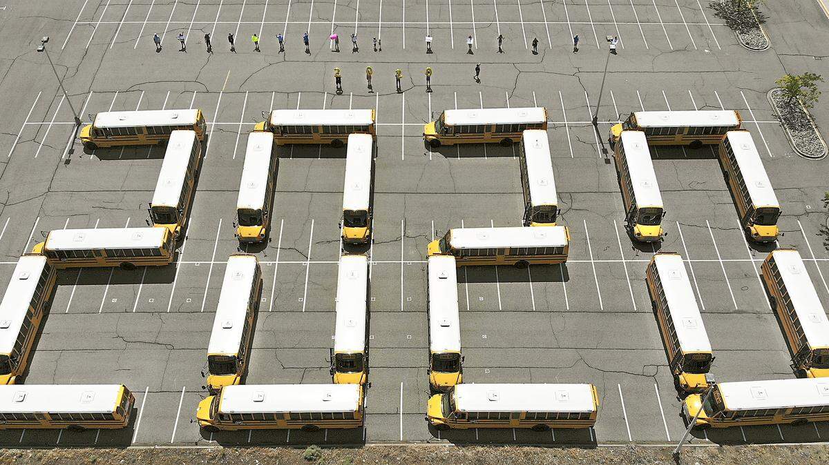 Kennewick School District transportation employees hold signs and balloons for a special end of school goodbye photo for the Class of 2020 and other students. Field representative Laurye Schmidt of Public School Employees of Washington said the special farewell used 22 buses in the parking lot of the Toyota Center in Kennewick.The photo was taken by a drone from 160 feet.