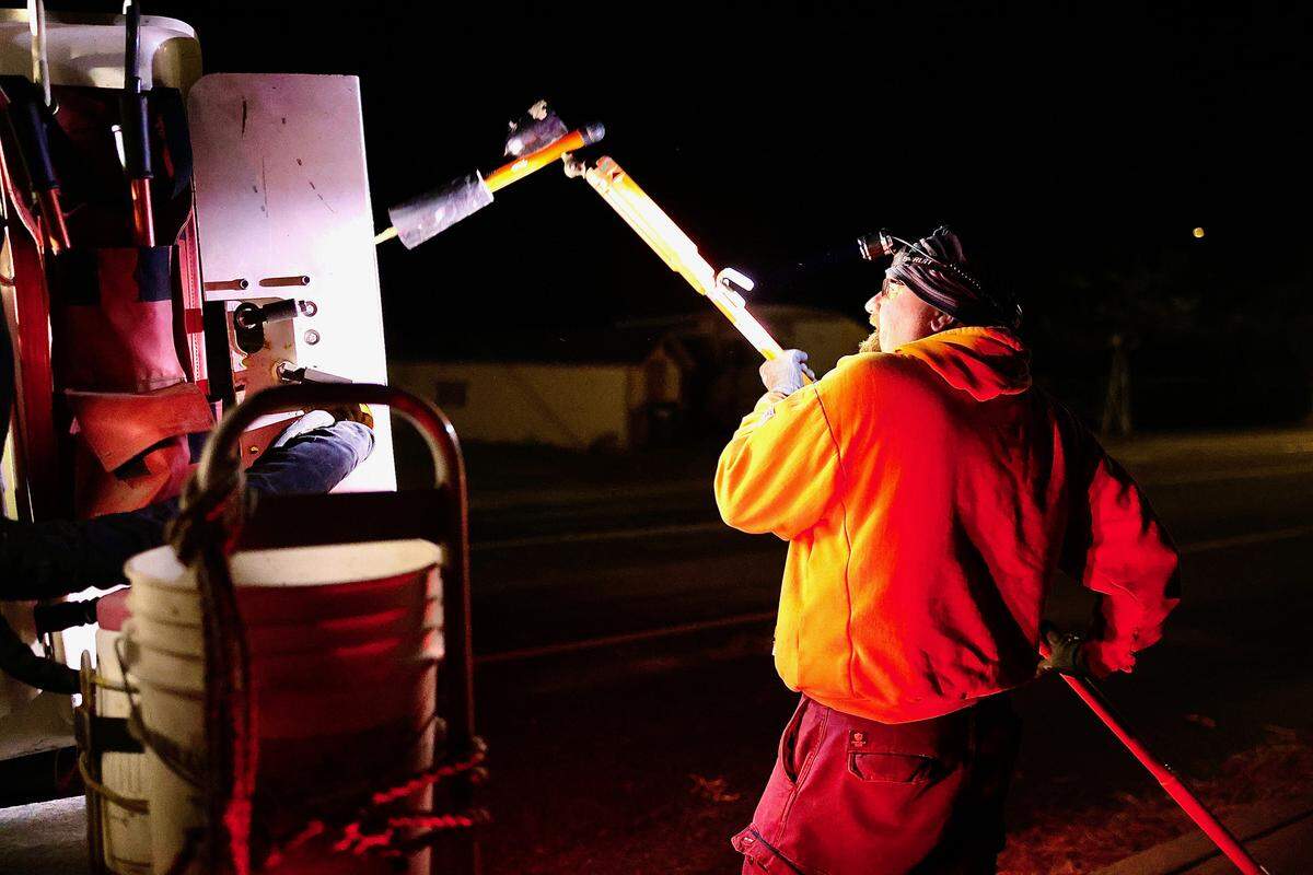 A Benton REA lineman works in the wind during the early morning Wednesday, preparing to disconnect power to repair a downed power line near North 62nd Avenue in West Richland.