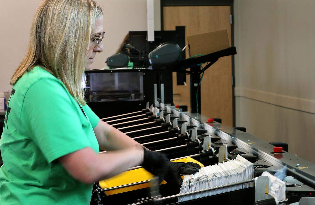 Lauren Miller, a Benton County elections center administrative assistant, works on the ballot sorting machine Monday in Kennewick. 