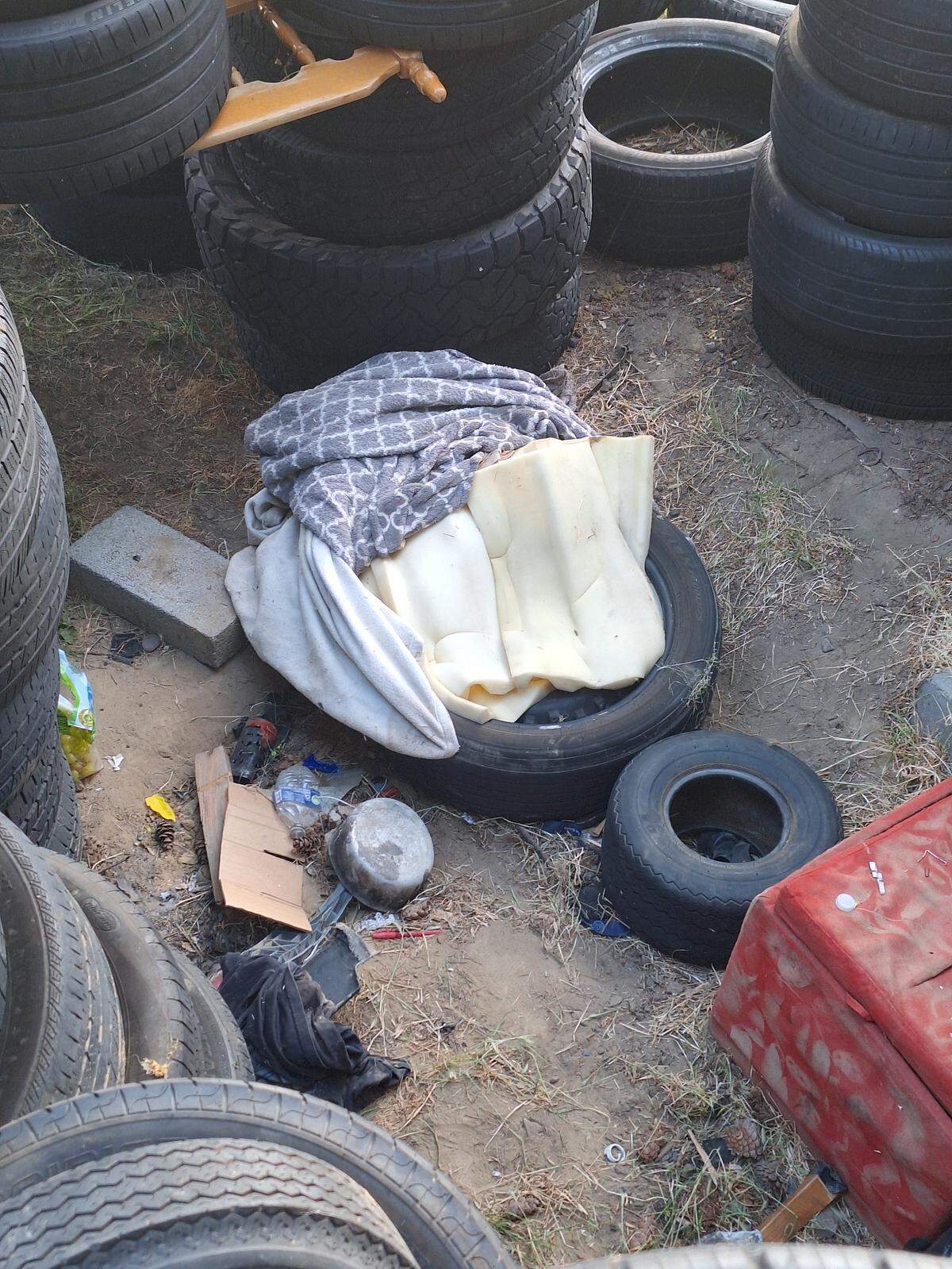 Part of a makeshift campsite is hidden behind piles of tires illegally dumped on a Kennewick property.