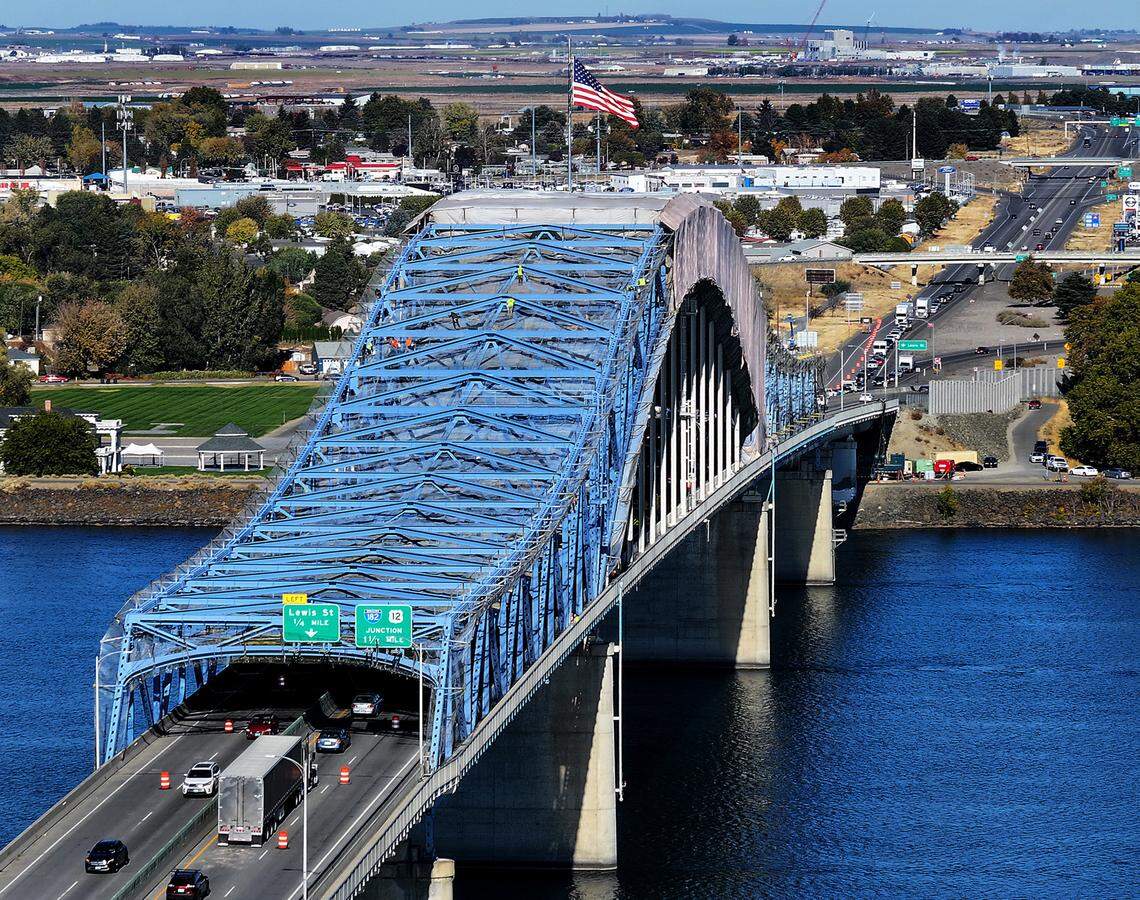 Workers are visible on the upper girders of the blue bridge as part of the $33.5 million project to repaint the span over the Columbia River continues into fall. Traffic is restricted to one lane in both direction on Highway 395 on the structure also known at the Pioneer Memorial Bridge.