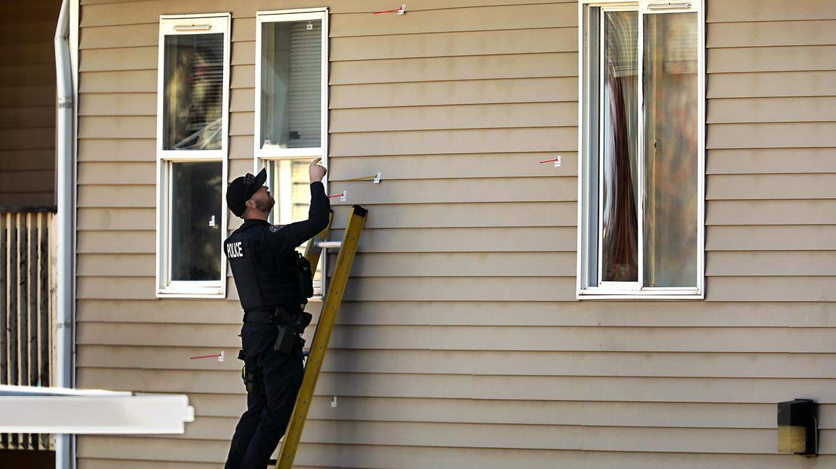 A Richalnd police investigator stands on a ladder Thursday morning identifying apparent bullet holes in the siding and windows of a second floor apartment unit at the Orchard Hills Apartment complex a 1845 Leslie Road in south Richland.