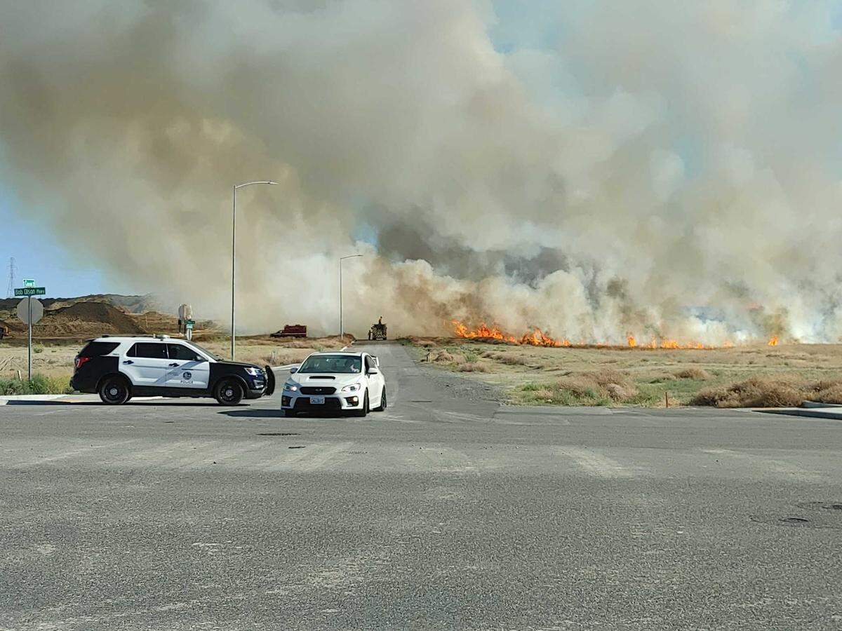 A wall of flames sweeps across open grassland south of Bob Olson Parkway near Colorado Street in Kennewick.
