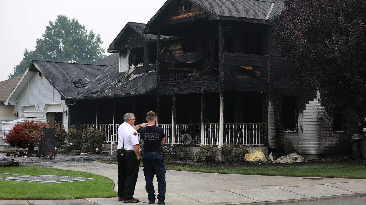 Pasco fire officials survey the heavily damaged home on the corner of Road 103 and West Court Street. One person was taken to the hospital with minor burns from the early morning blaze. The cause is under investigation.