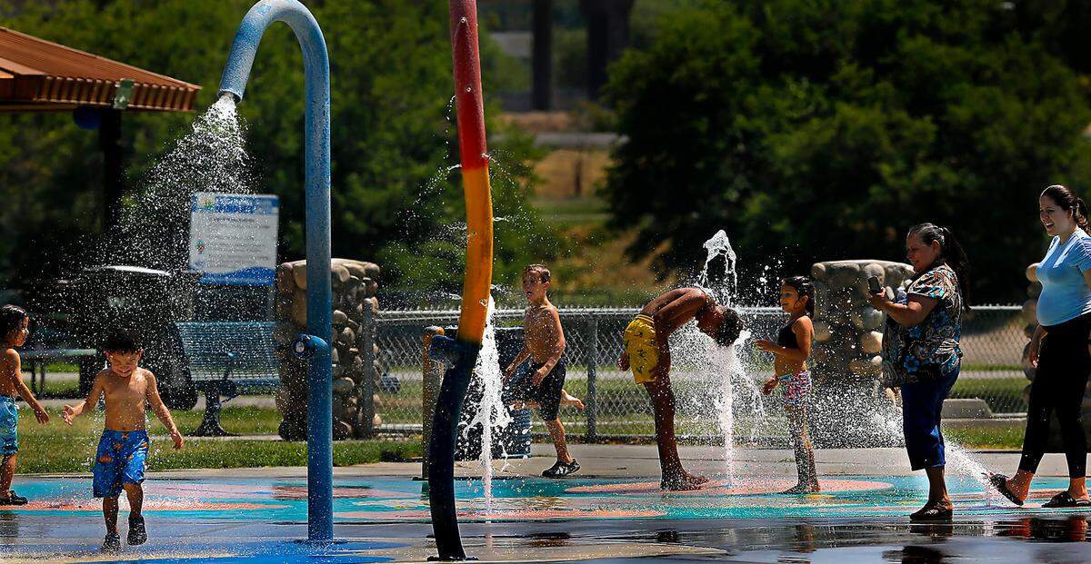 Kids and adults chill out at the splash pad at the Playground of Dreams on a hot and sunny summer afternoon at Kennewick’s Columbia Park. 