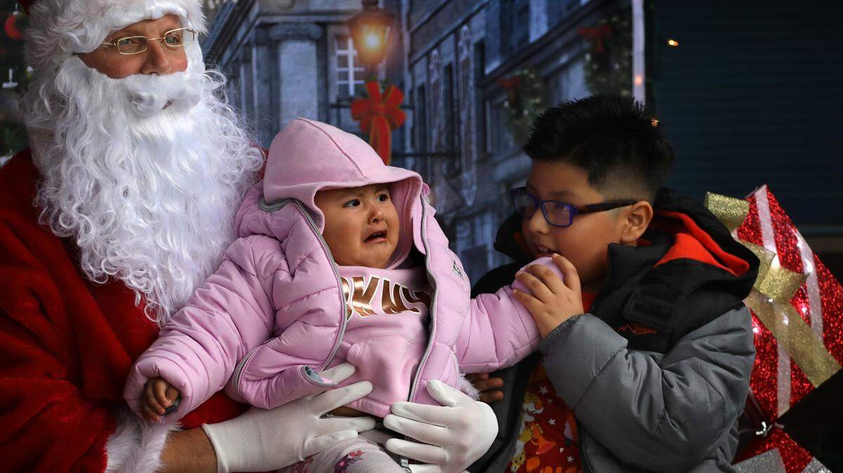 Jonathan Rojas, 7, tries to reassure his younger sister, Daisy, 2, during their visit to Santa Claus at the annual Christmas event by the Kennewick Irrigation District to collect new toys for donation to the Marine Toys for Tots Foundation.